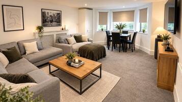 A modern living room with a sofa set, a coffee table, a dining area with chairs, and a fireplace.