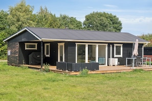 A single-story building with a covered patio area, large windows, and a chimney. - Cozy holiday home in Klint – Nykøbing Sj. (Nykøbing Sjælland)