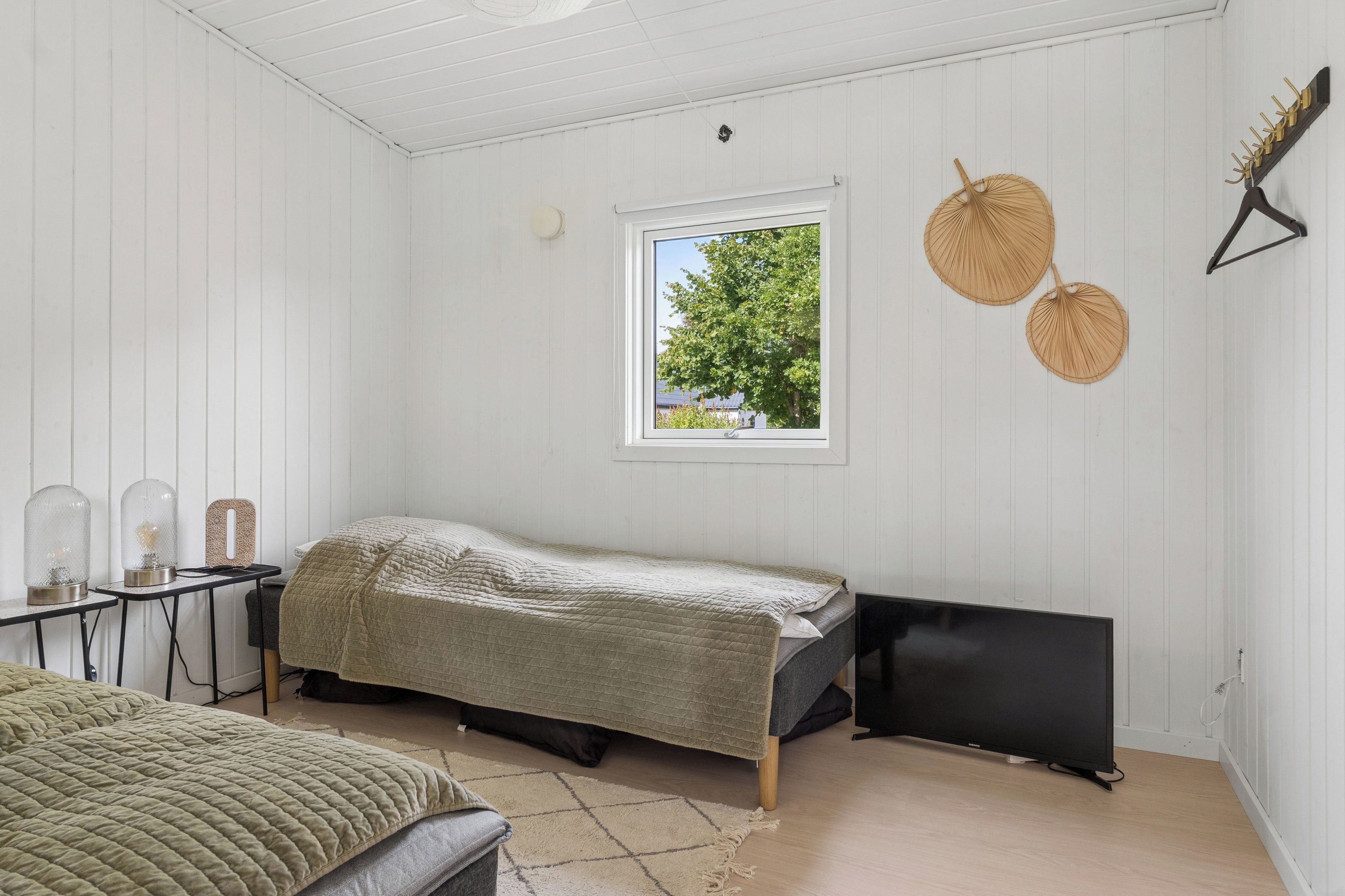 A room with a bed, a window, and a wall-mounted shelf with decorative items.