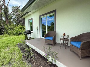 A patio with wicker furniture, a grill, and a table with a bottle and glasses. - 20 Min to Englewood Beach • Park + BBQ (Port Charlotte)
