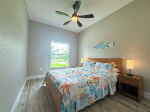A bedroom with a bed, a nightstand, a ceiling fan, a window, and a wall decoration. - 20 Min to Englewood Beach • Park + BBQ (Port Charlotte)
