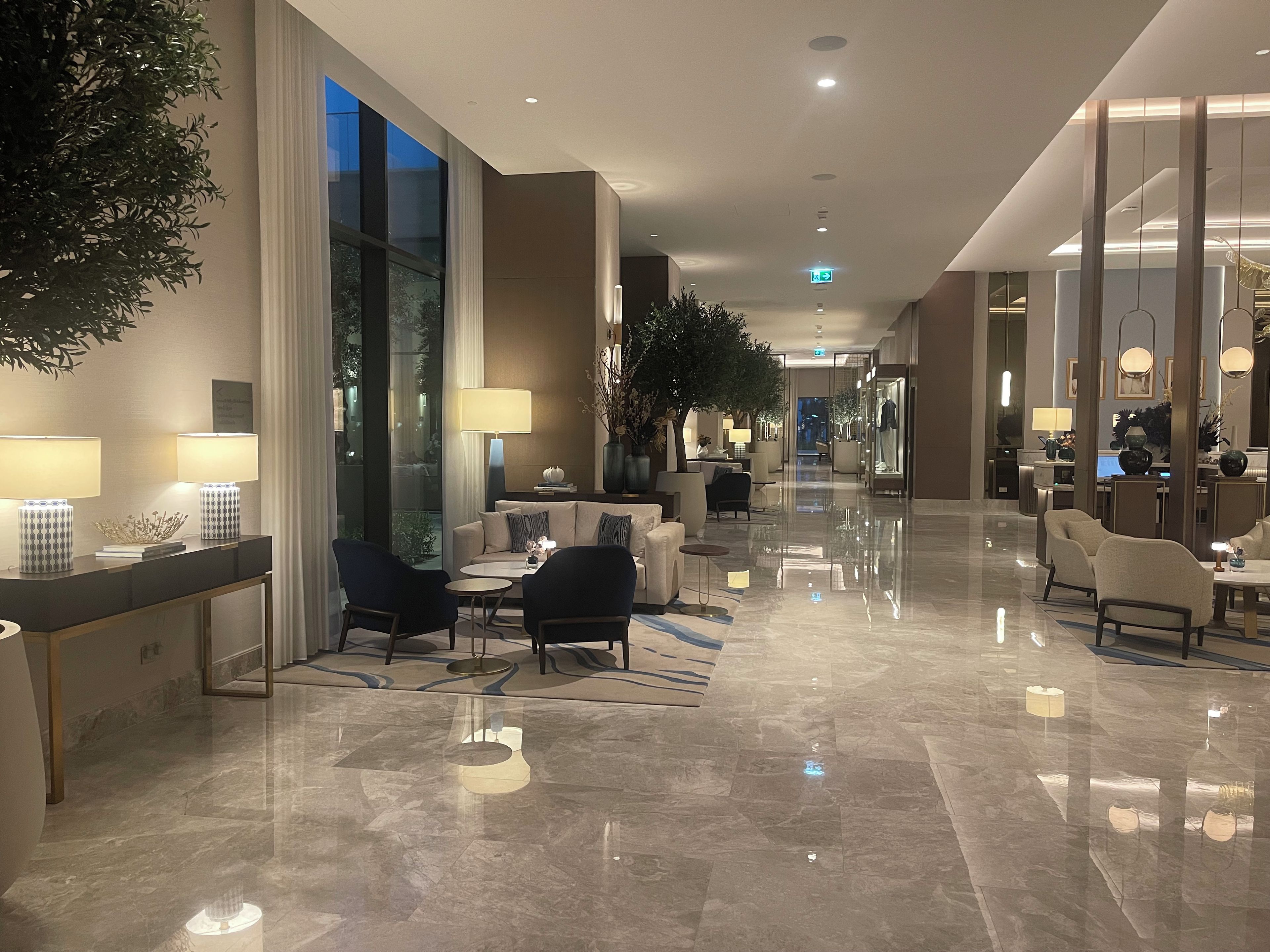 Eine geräumige Hotelhalle mit poliertem Marmorboden, Sitzgelegenheiten und großen Fenstern.