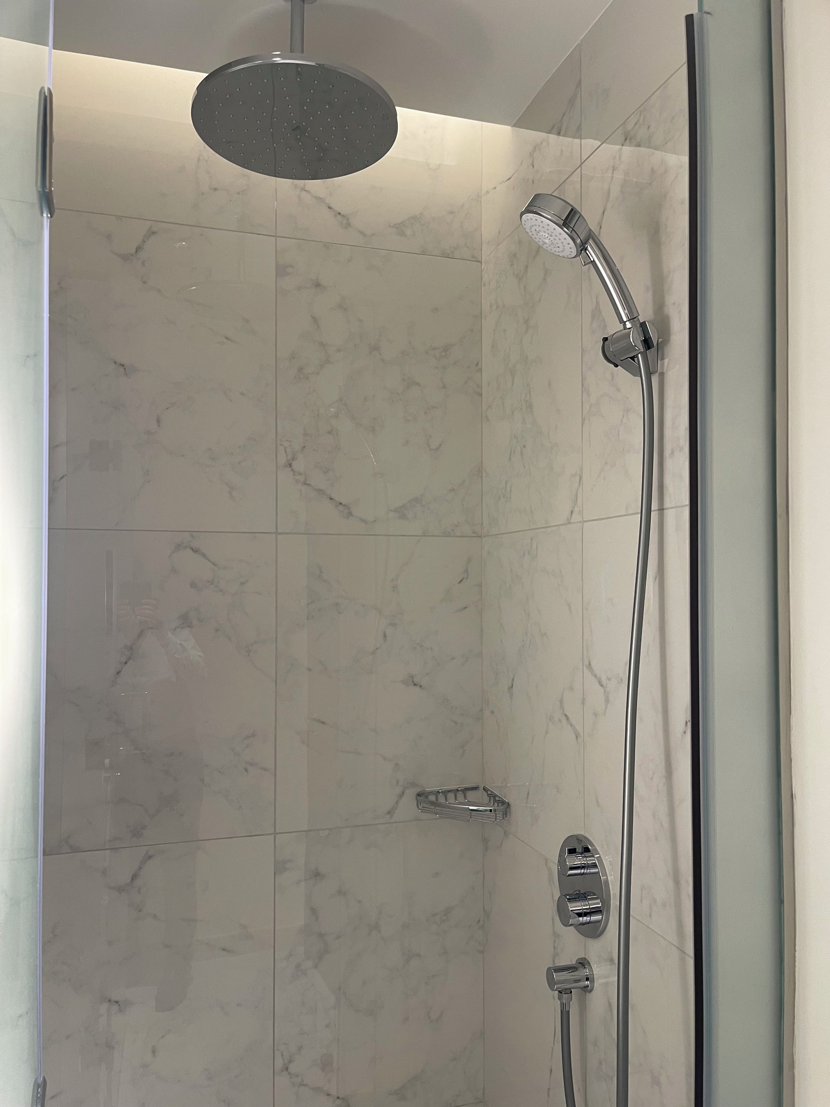 Een moderne douche met een handdouche en een kraan op de muur.