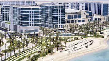 A modern hotel complex with multiple buildings, a beachfront, and a well-maintained garden area.