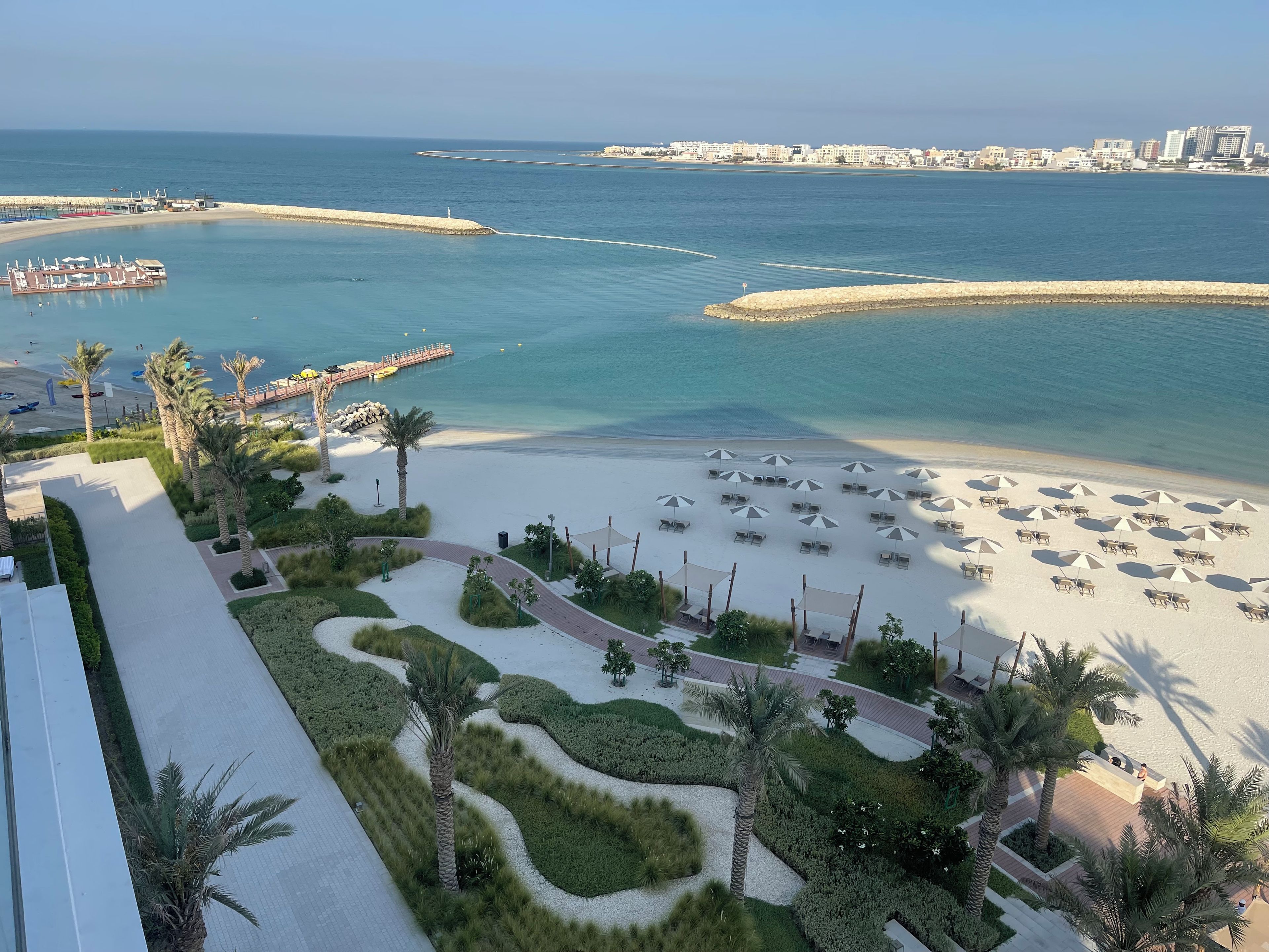 A coastal resort with a sandy beach, palm trees, and a marina.