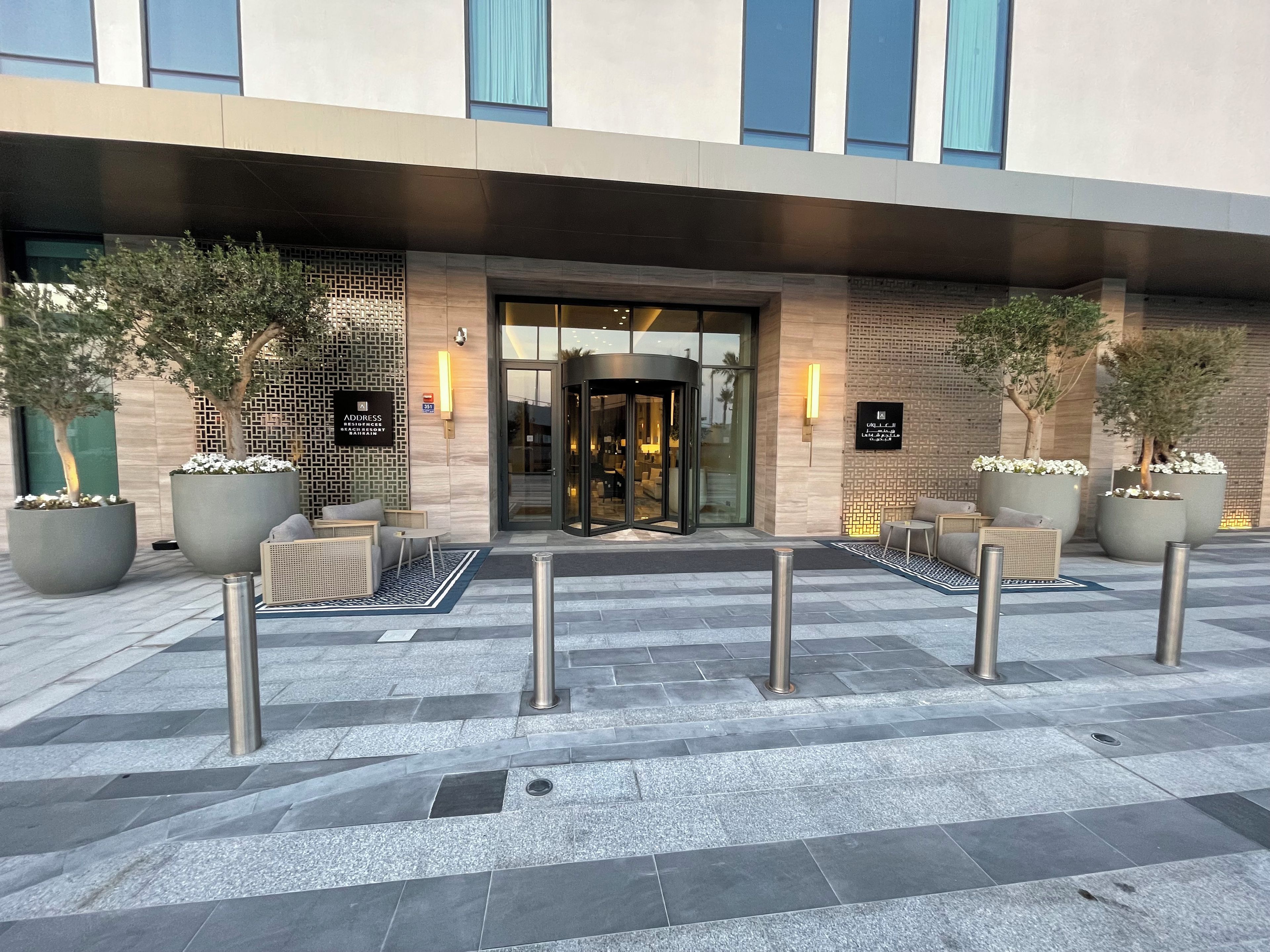 L’entrée d’un hôtel, avec une porte tournante, des plantes en pot et des sièges à l’extérieur.