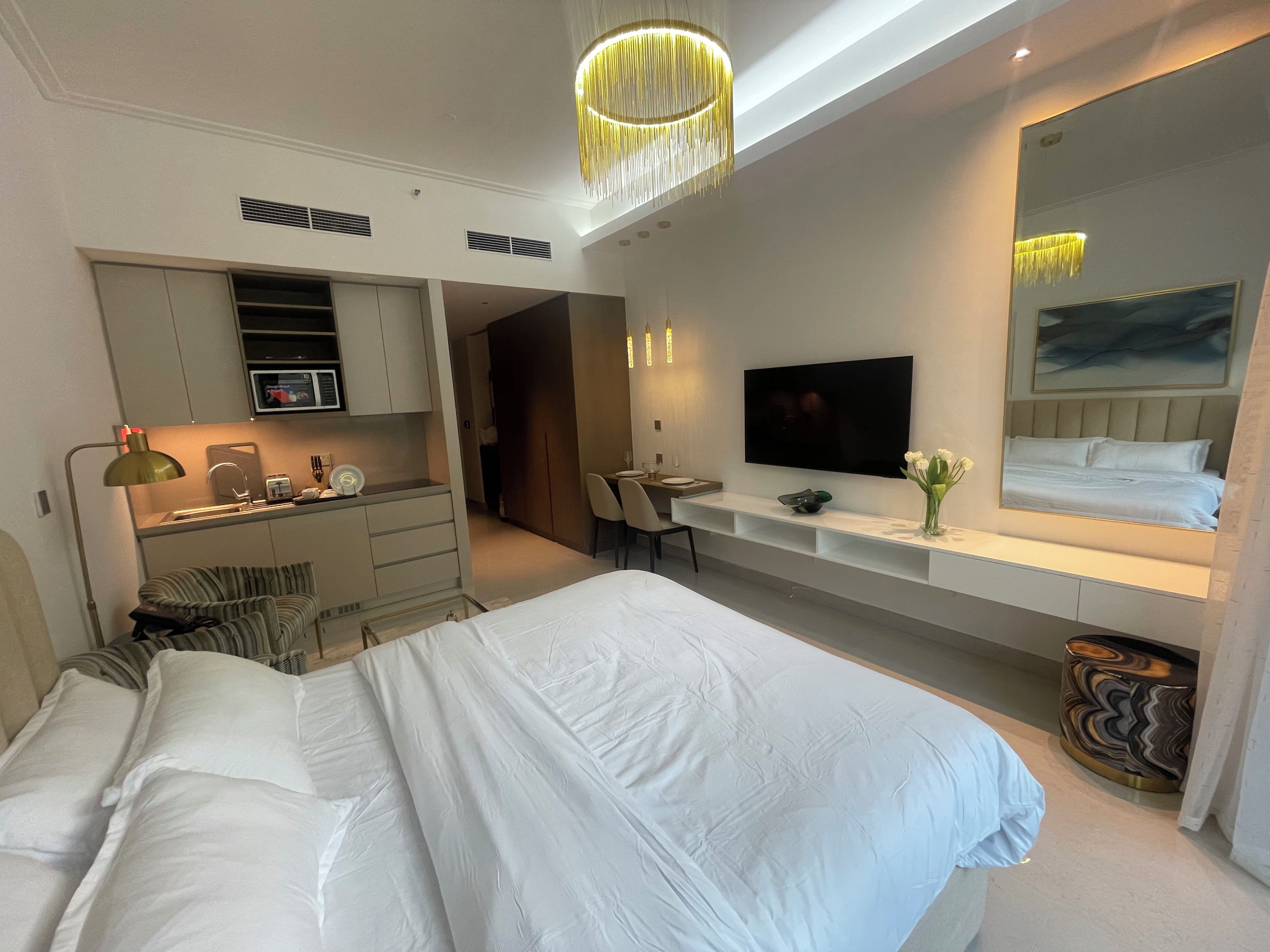 Une chambre d’hôtel moderne équipée d’un grand lit, d’un bureau, d’une télévision et d’un miroir.