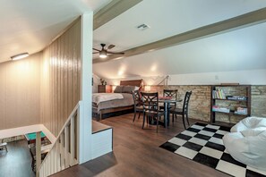 Ein Schlafzimmer mit einem Bett, Nachttisch, Lampe und einem Bücherregal mit Büchern.