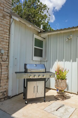A portable barbecue grill with four burners, a storage cabinet, and a flower pot. - Historic 1800s Rock House w/ horse corral (Gatesville)