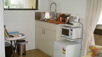 A compact kitchenette with a sink, a microwave, and a small refrigerator.