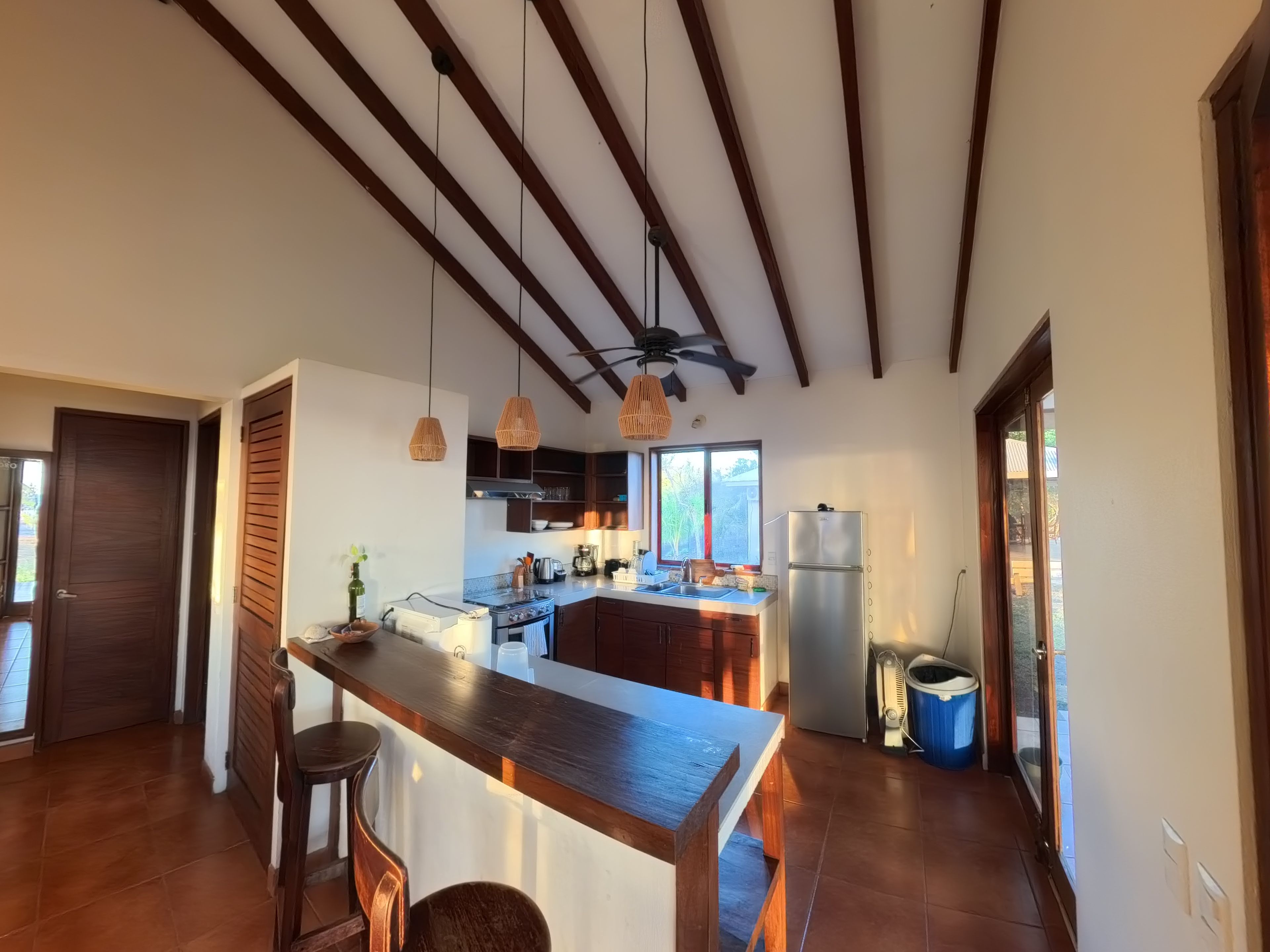 A kitchen with a wooden island, pendant lights, and a view to the outside.