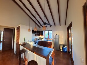 A kitchen with a wooden island, pendant lights, and a view to the outside.