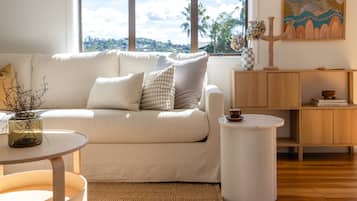 A modern living room with a sofa, a round side table, a cabinet, and a painting on the wall.