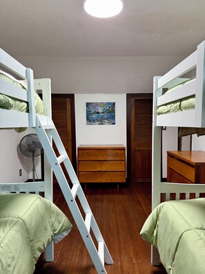 A dormitory room with bunk beds, a wooden dresser, a ladder, a fan, and a painting on the wall. - Charming 3-bedroom Cottage in Cleverdale on Beautiful Lake George with AC, WiFi (Queensbury)