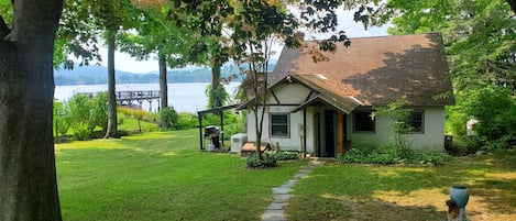 Una casa con un camino de piedra que conduce a la puerta principal, rodeada de abundante vegetación y vistas a un lago.
