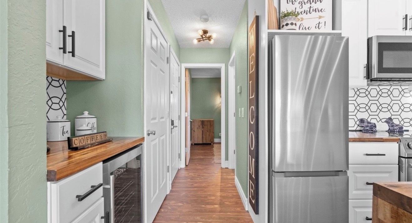 A kitchen with white cabinets, a stainless steel refrigerator, and a microwave.