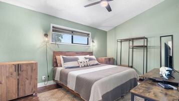 Un dormitorio con cama, escritorio, armario y ventilador de techo.