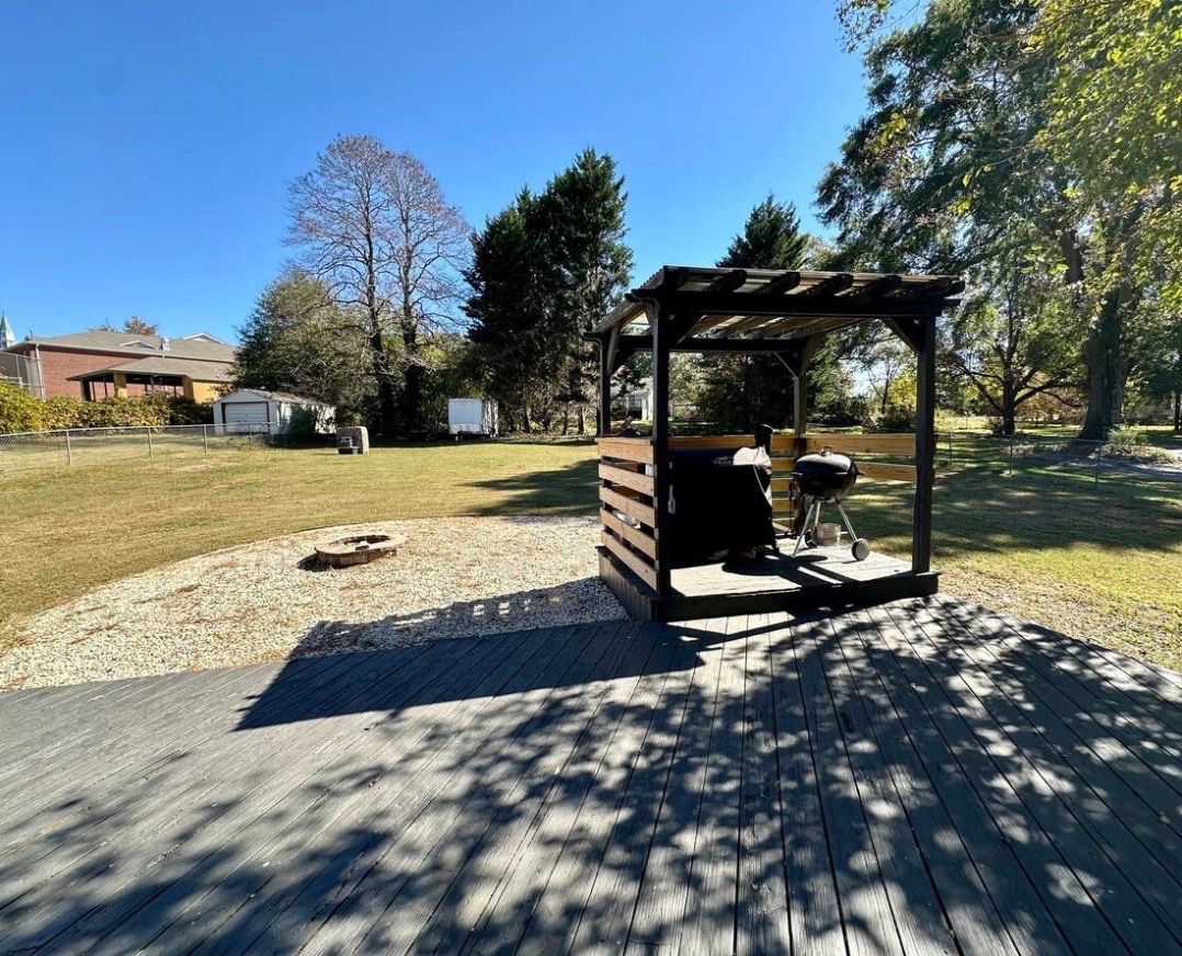 Un belvédère avec un barbecue, un foyer et une terrasse en bois.