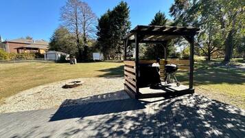 Un belvédère avec un barbecue, un foyer et une terrasse en bois.
