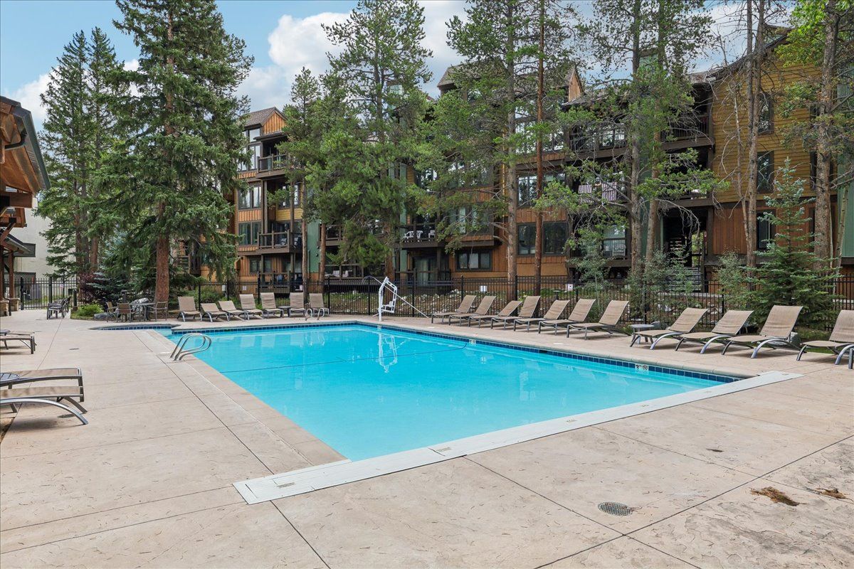 A swimming pool with lounge chairs and a wooden building with balconies.