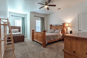 A bedroom with two wooden beds, a ceiling fan, a nightstand, and a dresser. - Bear Basecamp/3BR/Game Room/Midterm Welcome (Waco)