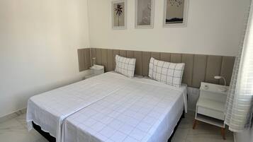 Una habitación de hotel con una cama grande, dos mesitas de noche y tres cuadros enmarcados en la pared.