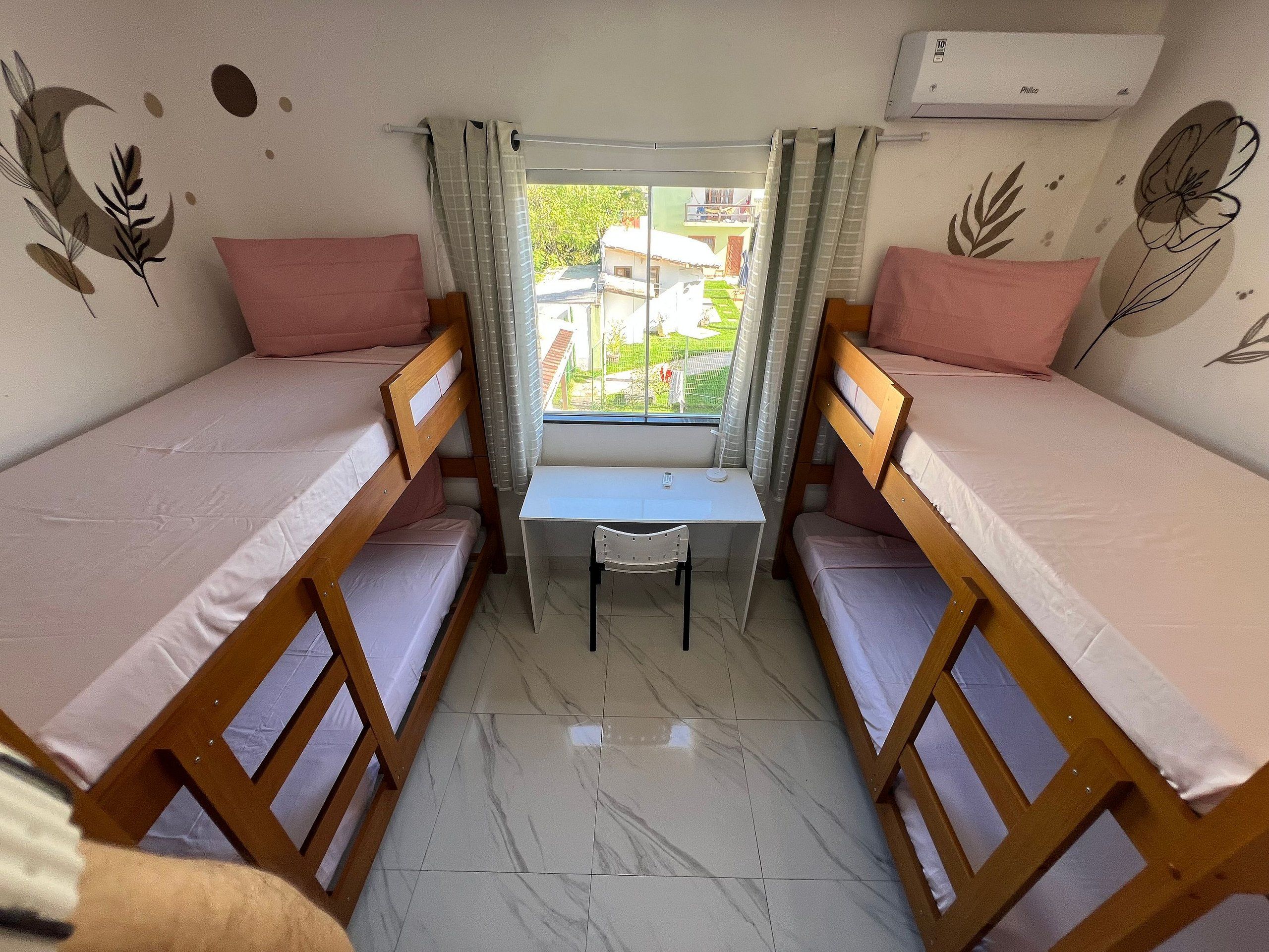 A dormitory room with bunk beds, a desk, and a window.