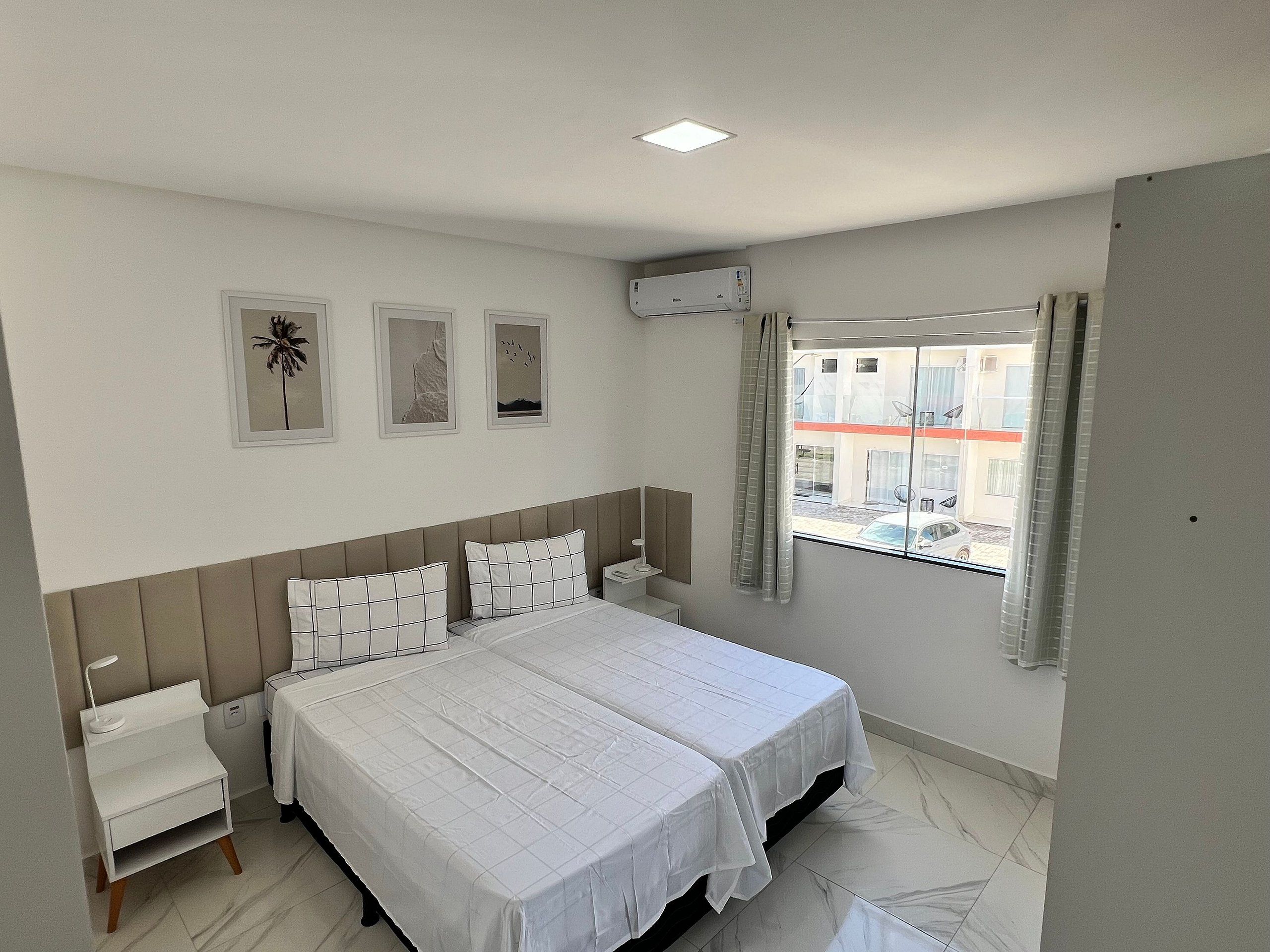 Une chambre d’hôtel avec un lit, des tables de chevet, une fenêtre avec des rideaux et des œuvres d’art murales.