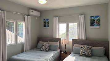 Une chambre avec deux lits, un ventilateur de plafond et une fenêtre avec des rideaux.
