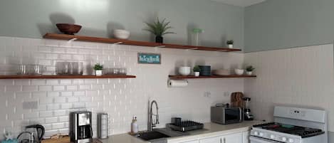 A kitchen with white cabinets, a coffee maker, a toaster, and a stove.