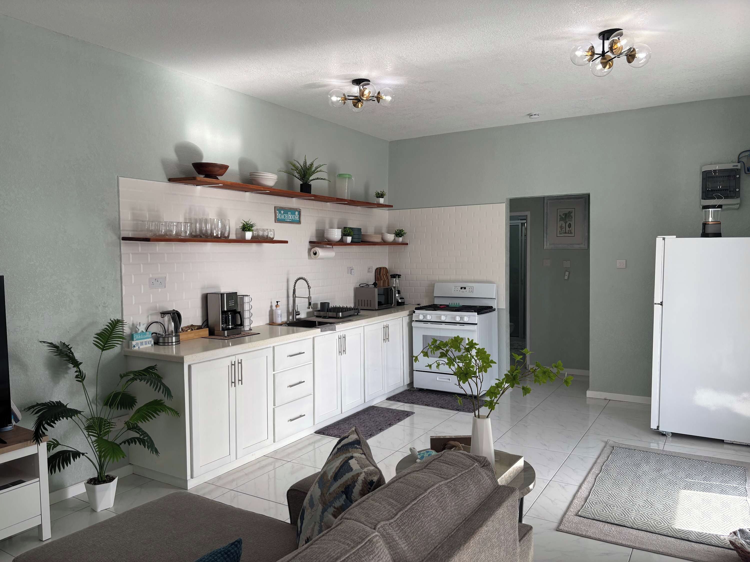 Una cocina moderna con armarios blancos, horno empotrado y refrigerador.