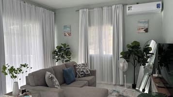 Un soggiorno con divano, un tavolino, uno specchio e una ventola a soffitto.