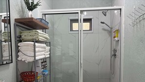 Een moderne badkamer met een douchecabine van glas, een toilet en een plank met opgevouwen handdoeken.
