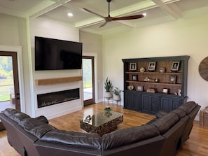 A living room with a fireplace, leather sofas, a television, and a wooden cabinet with decorative items.