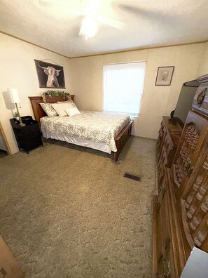 A bedroom with a bed, a nightstand, a dresser, a ceiling fan, and a window with blinds. - Newly renovated 3-bedroom mobile home in beautiful Louisa. (Louisa)