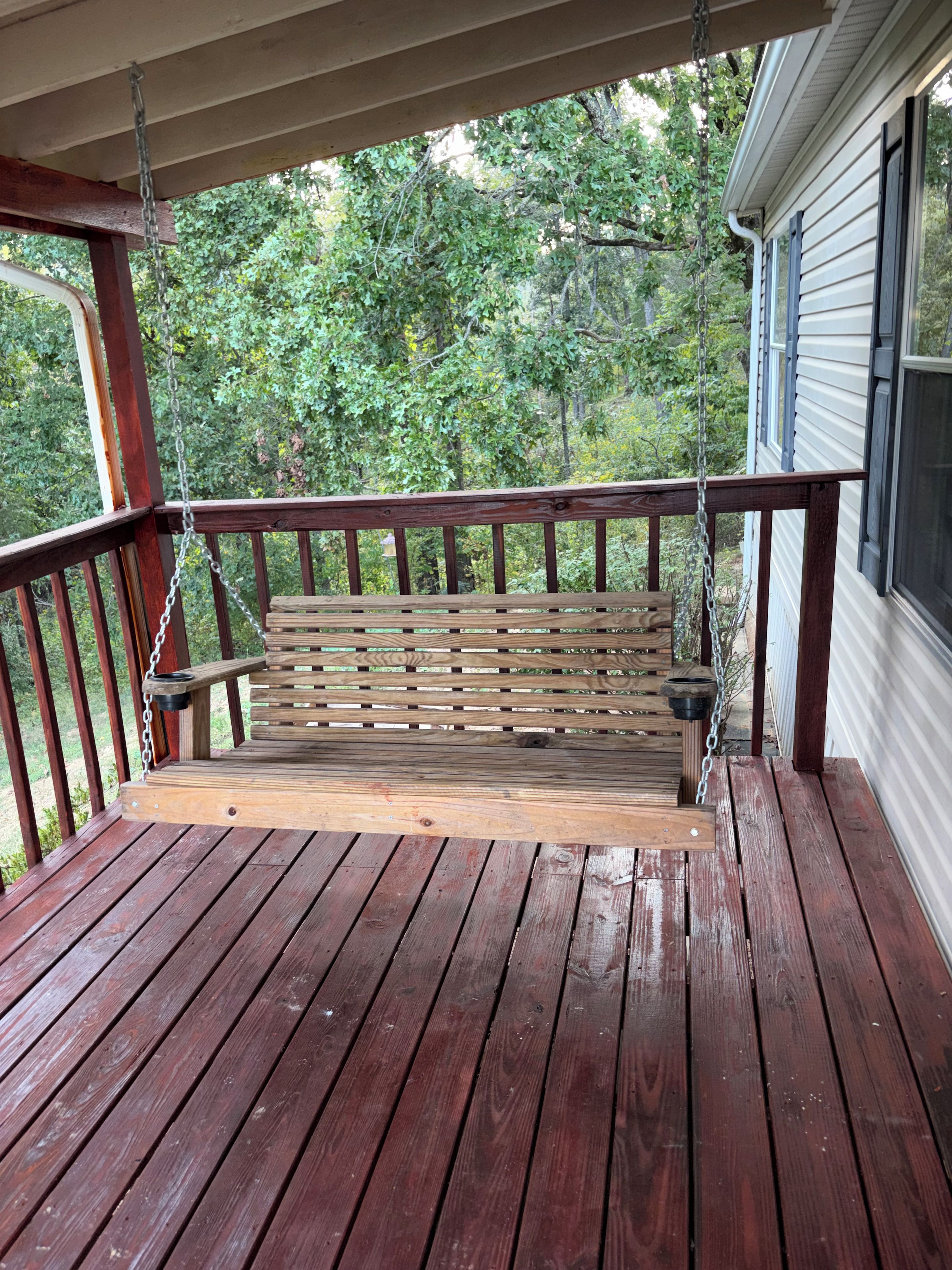 Eine Holzterrasse mit einer Bank und einer Schaukel.