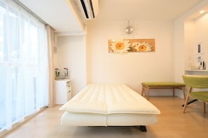 A room with a bed, a small table, a chair, and a wall clock.