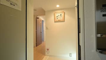 A hallway with a door leading to another room, a framed artwork on the wall, and a sign with Japanese text.