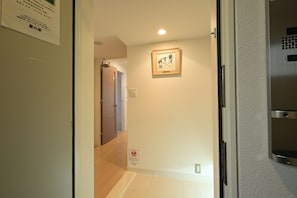 A hallway with a door leading to another room, a framed artwork on the wall, and a sign with Japanese text. - 1-minute walk from Nihonbashi Station (subway) · 1 minute to Dotonbori · 1-minute bus ride from Kuromon Market/Namba/Shinsaibashi to Kansai Airport – convenient location / luxury apartment with two elevators (Osaka)