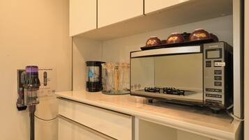 A kitchen with a microwave, a Dyson vacuum cleaner, and a coffee maker on the counter.