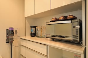 A kitchen with a microwave, a Dyson vacuum cleaner, and a coffee maker on the counter.