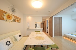 A modern living room with a dining table, sofa, and a large decorative wall piece. - 1-minute walk from Nihonbashi Station (subway) · 1 minute to Dotonbori · 1-minute bus ride from Kuromon Market/Namba/Shinsaibashi to Kansai Airport – convenient location / luxury apartment with two elevators (Osaka)