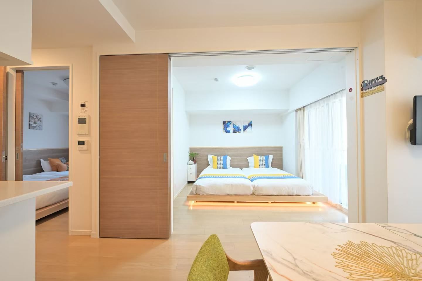 A hotel room with a bed, bedside table, and a view of the hallway.