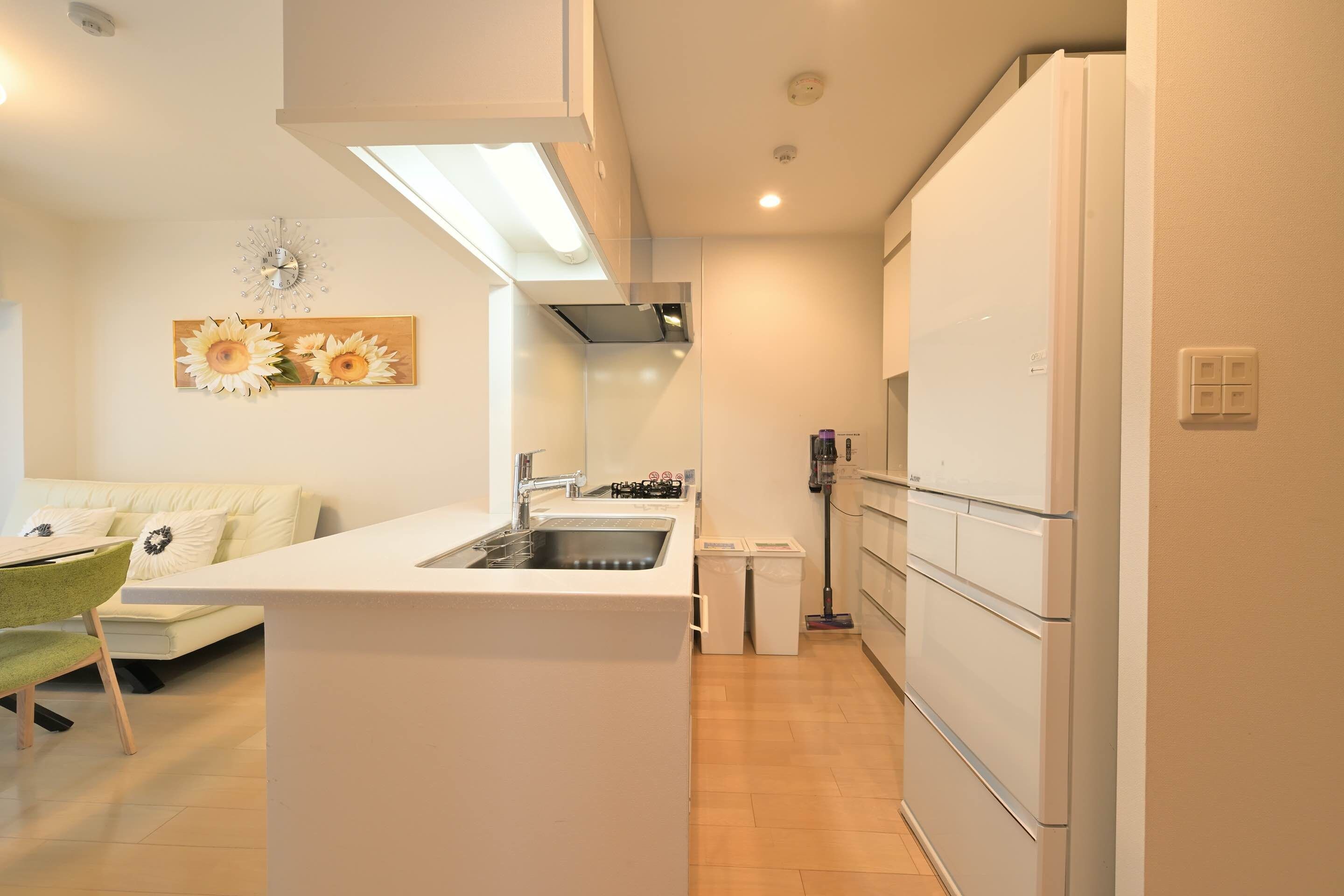 A modern kitchen with a central island, a built-in oven, and a refrigerator.