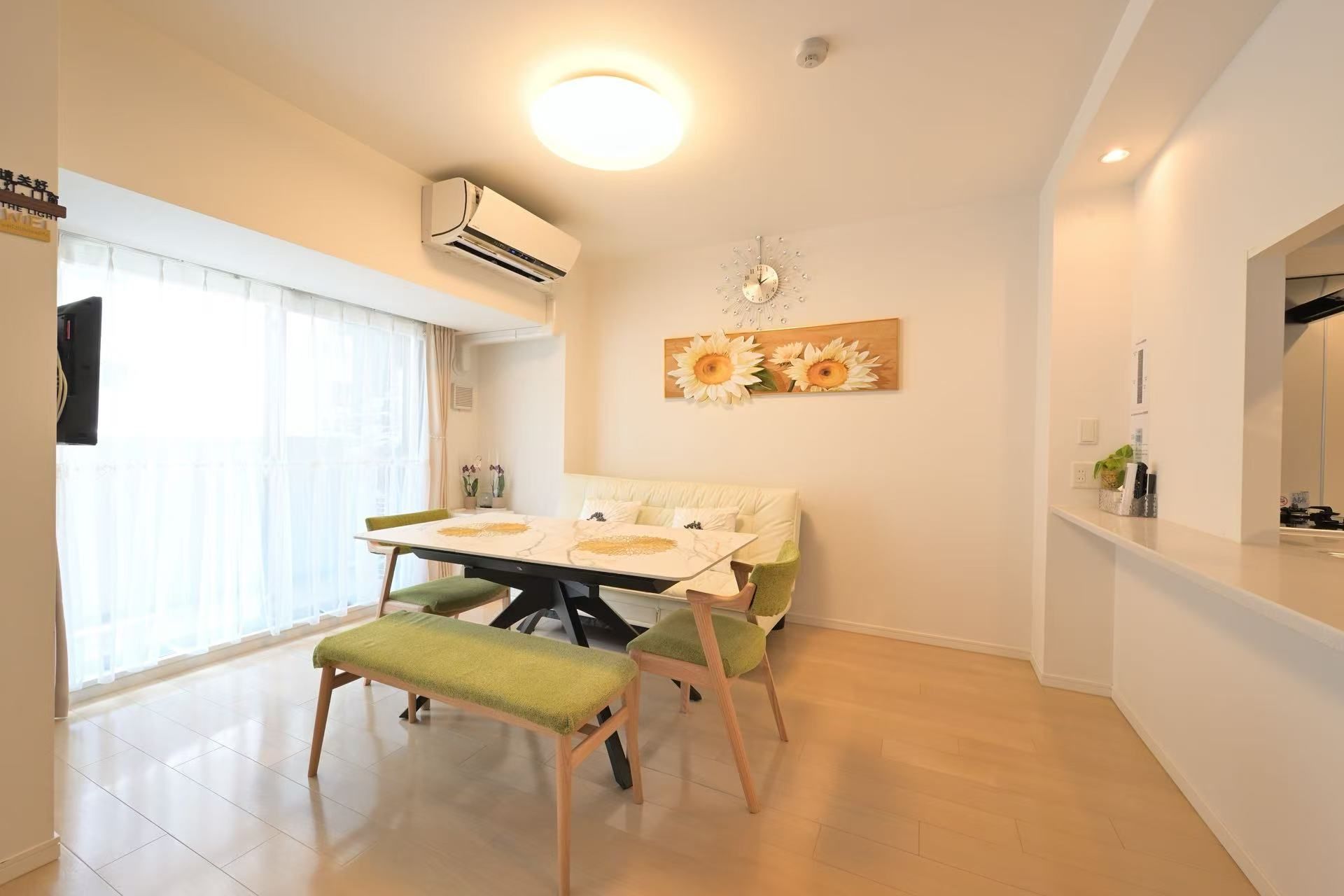 A dining area with a table, chairs, and a wall-mounted clock.