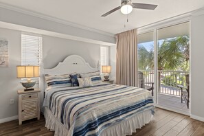 Ein Schlafzimmer mit einem Bett, zwei Nachttischen, einem Deckenventilator und Blick ins Freie.
