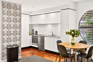 Eine moderne Küche mit weißen Schränken, Edelstahlgeräten und einem Essbereich mit rundem Tisch und Stühlen.