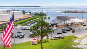 A parking lot with a Joe Patti restaurant, a flag, and a view of the water. - Sabine Yacht & Racquet Club 6C | Spectacular Pensacola Beachfront Views | Beach Svc (Pensacola Beach)