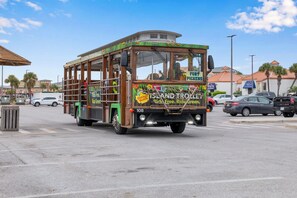 Un chariot en bois, conçu pour être placé au milieu d’une rue, portant les inscriptions « Profitez de la liberté » et « Adoptez une conduite écologique », est stationné dans une rue, avec des voitures et des bâtiments en arrière-plan.
