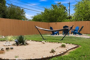 A backyard with a wooden fence, a hammock, blue chairs, and a cactus. - Agave - A Birdy Vacation Rental (San Antonio)